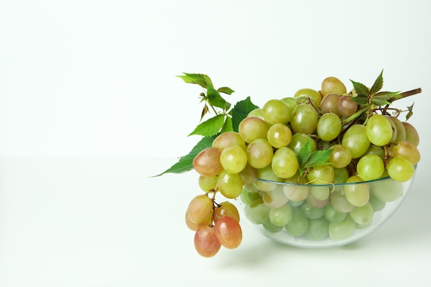 Bowl with green grape on white background, space for text