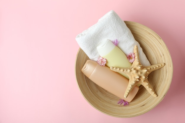 Bowl with hair care accessories on pink