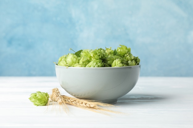 Bowl with hop and spikelets on white wooden table