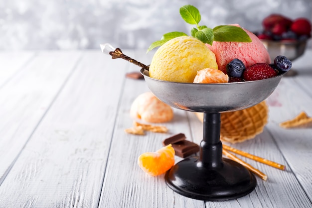 Чаша с мороженым с тремя различными ложками желтого, красного цветов и вафельного конуса