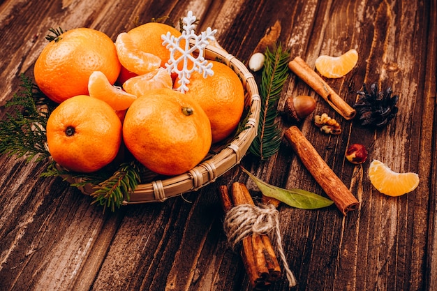 Bowl with little tangerines stands on the wooden table with species for Christmas drinks 