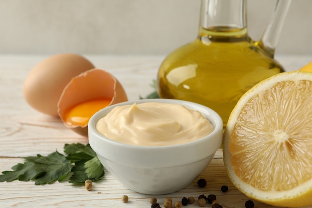 Photo bowl with mayonnaise and ingredients for cooking on wooden background