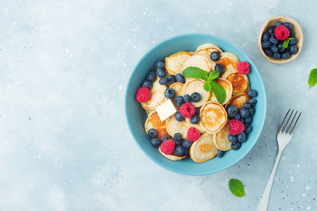 Bowl with mini pancakes cereal with butter and berries