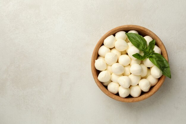 Ciotola con mozzarella e basilico su sfondo bianco con texture, spazio per il testo