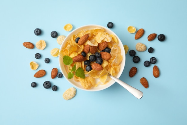 Bowl with muesli, almond, mint and blueberry on blue background