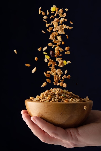 Bowl with muesli in hand. muesli is poured into a bowl