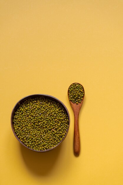 Ciotola con fagioli mung su uno sfondo giallo. cibo ecologico, piatti ecologici.