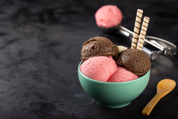 Bowl with Neapolitan ice cream on dark background.