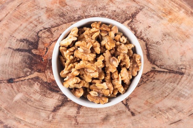 Bowl with nuts and wooden background top view