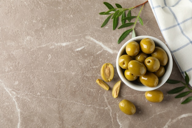 Bowl with olives, leaves and towel on grey, space for text