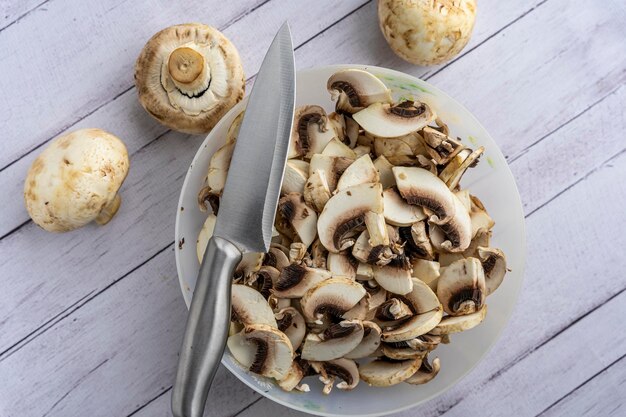 A bowl with pieces of fresh mushrooms cut the mushrooms with a knife