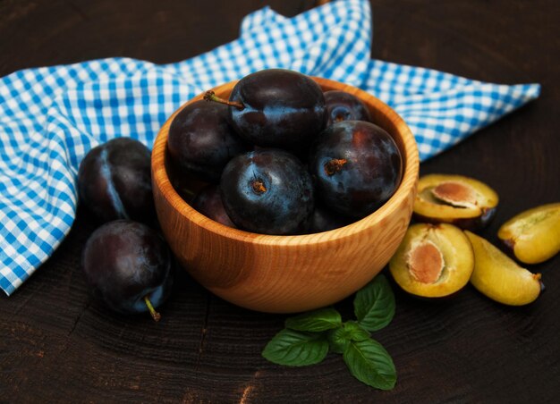 Bowl with plums with green leaves