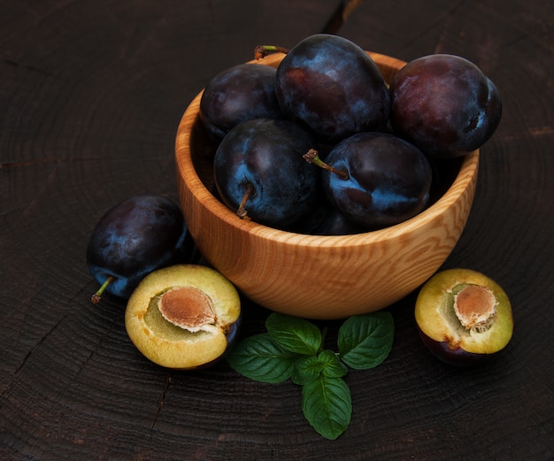 Bowl with  plums with green leaves