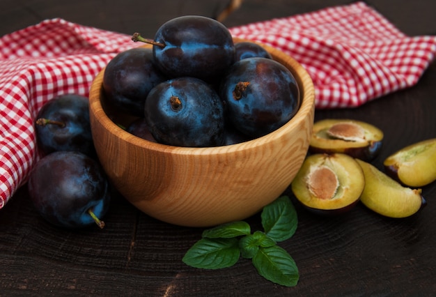 Bowl with  plums with green leaves