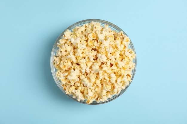 Bowl with popcorn on blue. Food for watching cinema