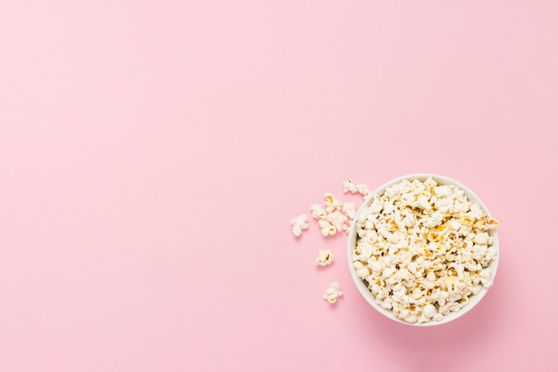 Bowl with popcorn on a pink background. Flat lay, top view.