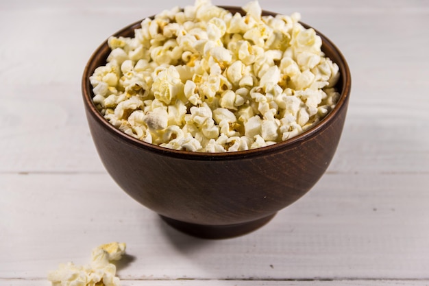 Bowl with popcorn on white wooden table