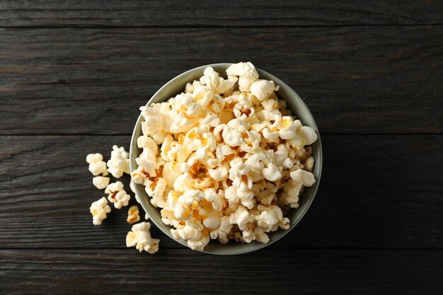 Bowl with popcorn on wooden background