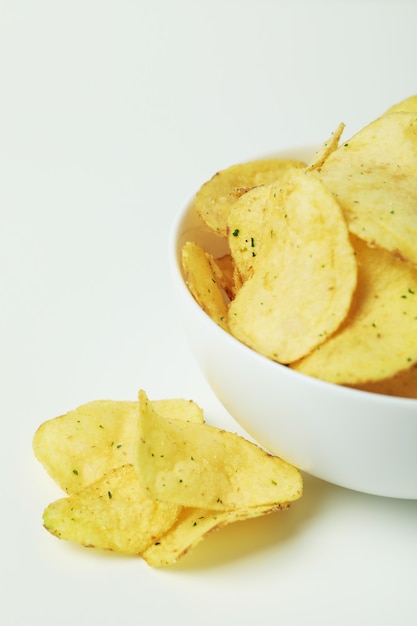 Bowl with potato chips on white surface