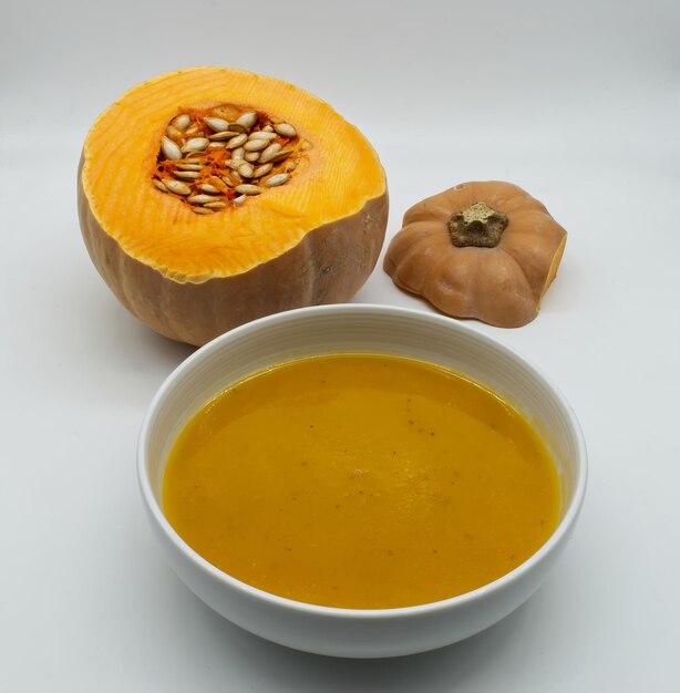 A bowl with pumpkin cream soup vellutata di zucca isolated on white background