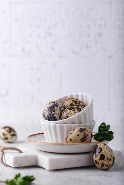 Bowl with quail eggs on light background