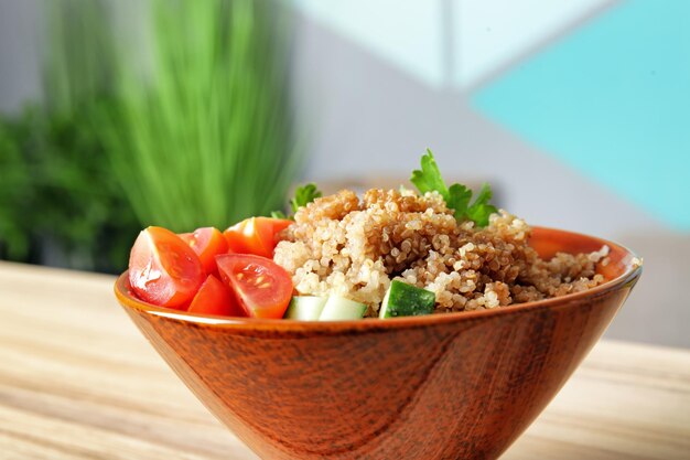 Bowl with quinoa salad on table