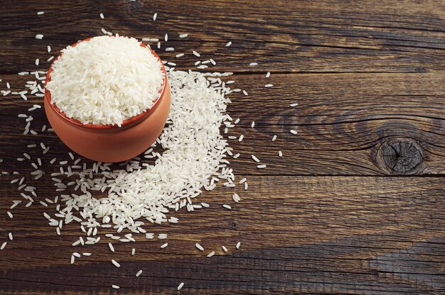 Bowl with raw rice on dark wooden table