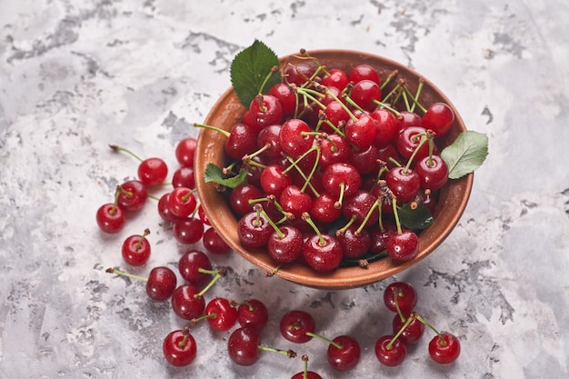 Bowl with red cherry on gray background