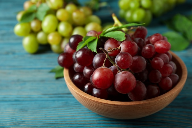 Bowl with red grape and green grape on wooden background