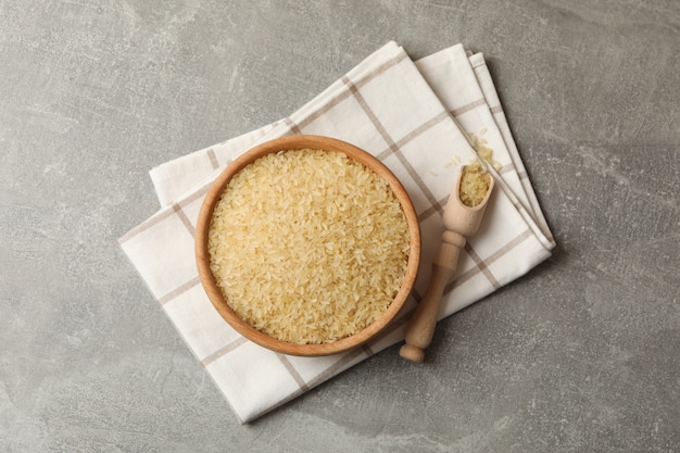 Bowl with rice, towel and spoon on grey surface