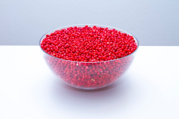 Bowl with ripe and fresh cowberries on white background.