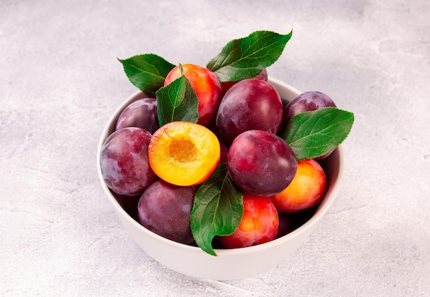 A bowl with ripe juicy plums on a gray background gifts of nature