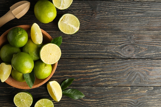 Bowl with ripe lime on wooden background, space for text