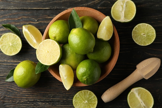 Bowl with ripe lime on wooden background, top view