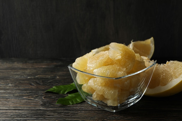 Bowl with ripe pomelo fruit slices on wooden table