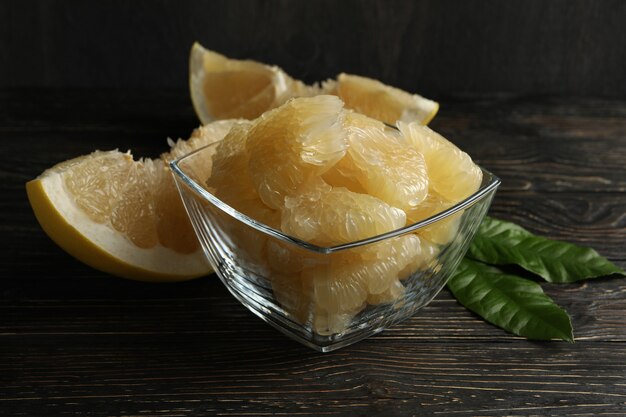 Bowl with ripe pomelo fruit slices on wooden table