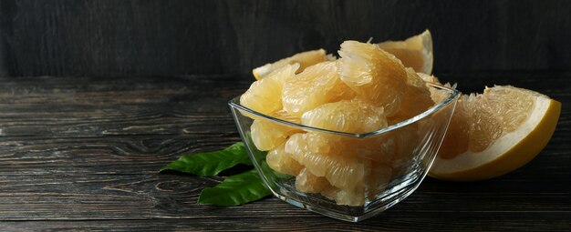 Bowl with ripe pomelo fruit slices on wooden table