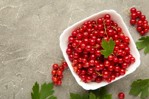 Bowl with ripe red currant on grey background Top view