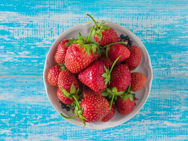 Bowl with ripe strawberries on a blue wood