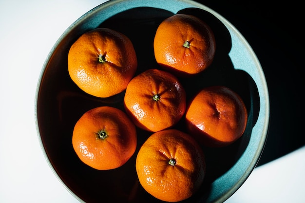 Bowl with ripe and unpeeled tangerines seen from above