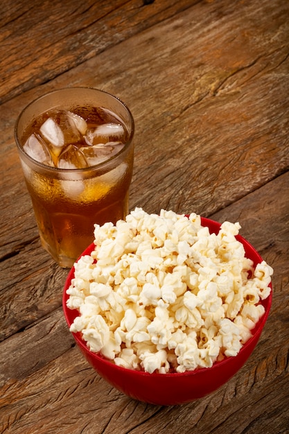 Bowl with salted popcorn and soda on the table
