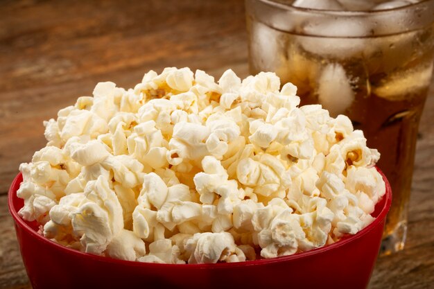 Bowl with salted popcorn and soda on the table