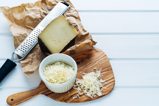 Foto ciotola con formaggio grattugiato su un tagliere. copia spazio.