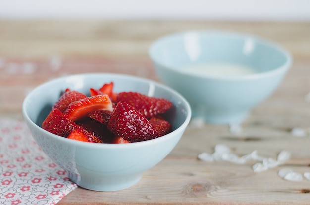 Bowl with strawberries on wooden background.