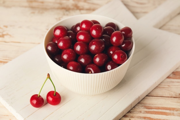 Bowl with sweet cherry on table