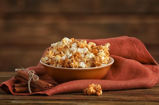 Bowl with tasty caramel popcorn on wooden table