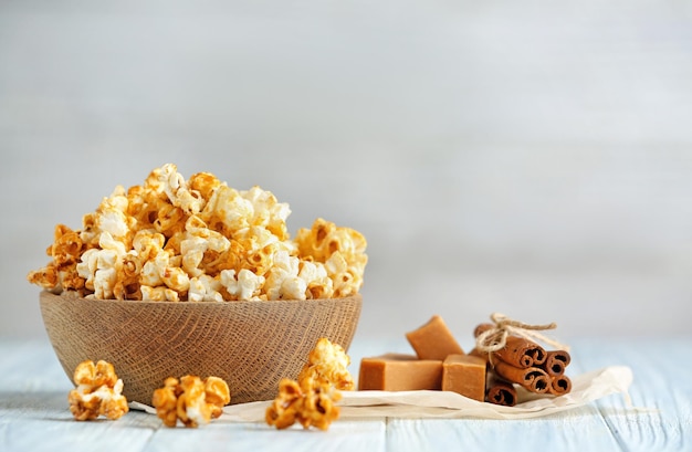 Bowl with tasty caramel popcorn on wooden table