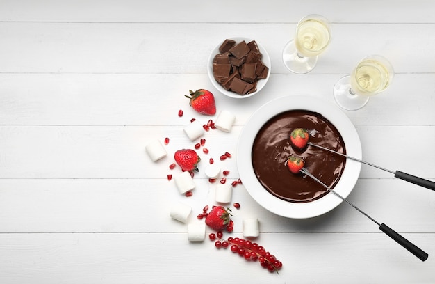 Bowl with tasty chocolate fondue, berries and marshmallow on table