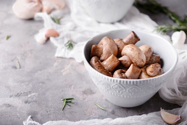 Bowl with tasty fermented mushrooms on grey table