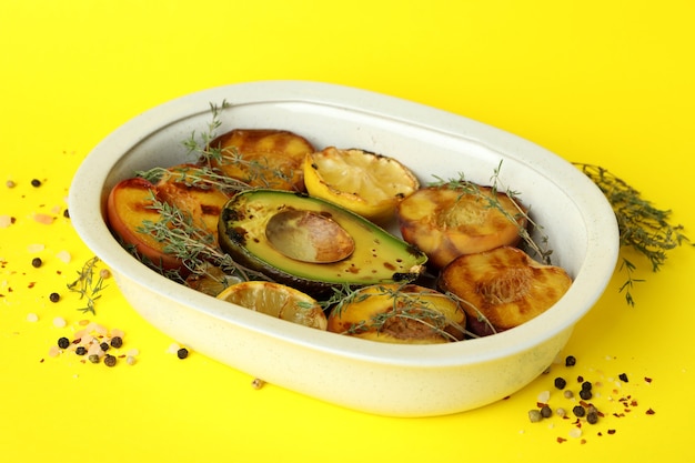 Bowl with tasty grilled peach on yellow background